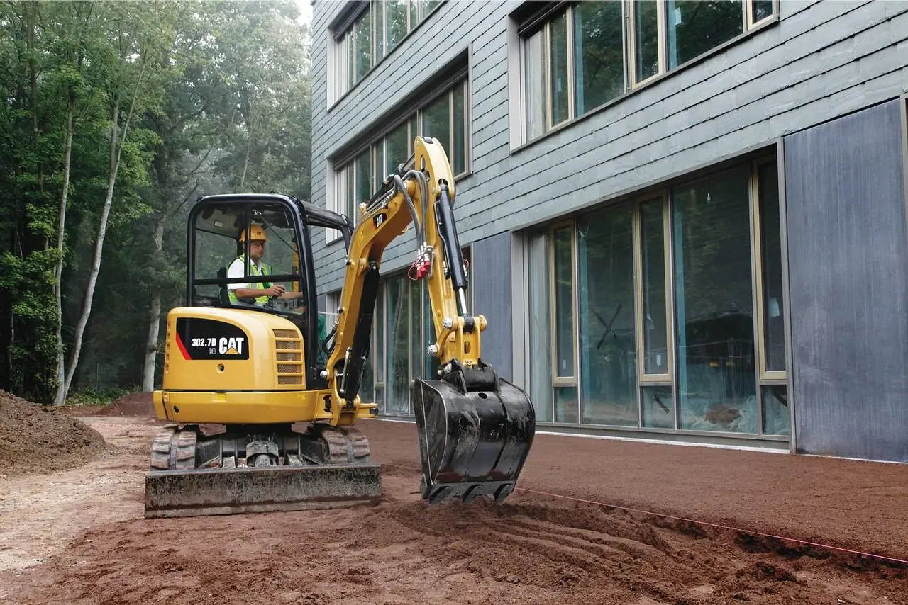 Compact excavator digging next to a building